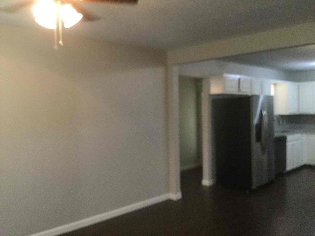 A kitchen with a black refrigerator and white cabinets.