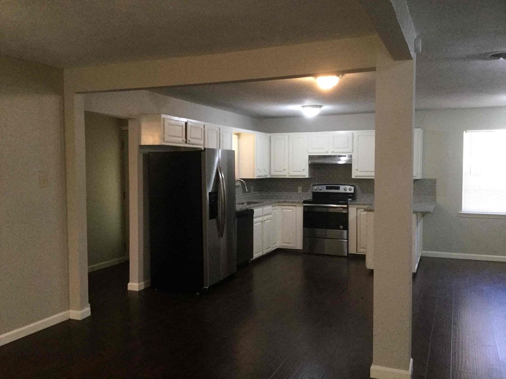 A kitchen with white cabinets and a black refrigerator.