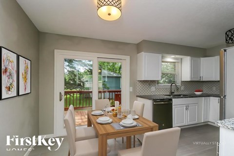 A dining room with a table set for two and a view of a balcony.