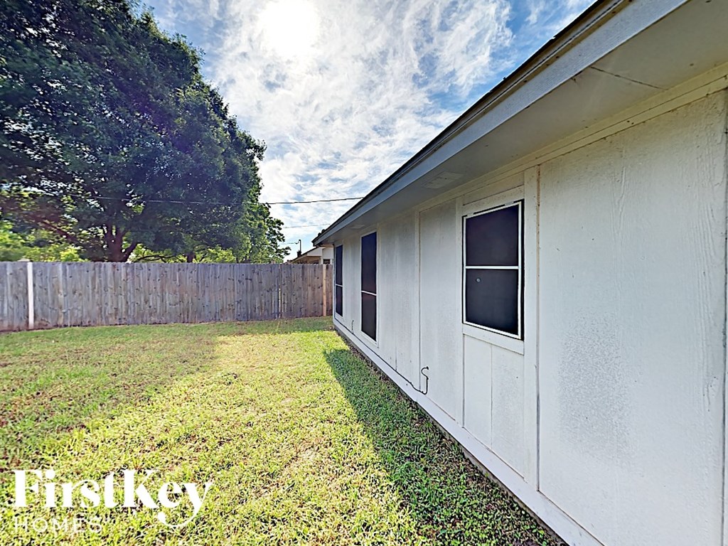 the side of a house with a yard and a fence