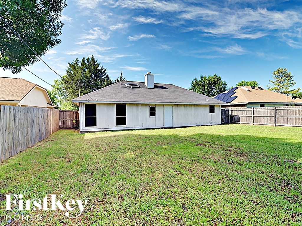 a backyard with a fence and a white house