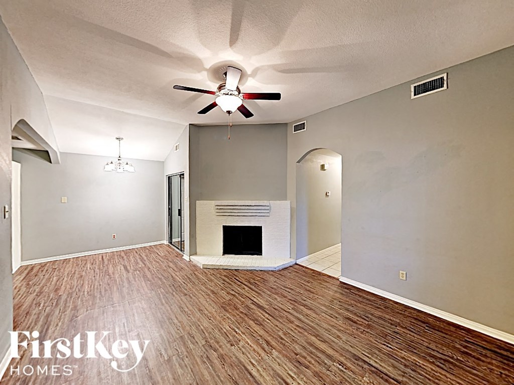an empty living room with a ceiling fan and a fireplace