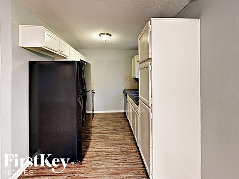 a kitchen with white cabinets and a black refrigerator