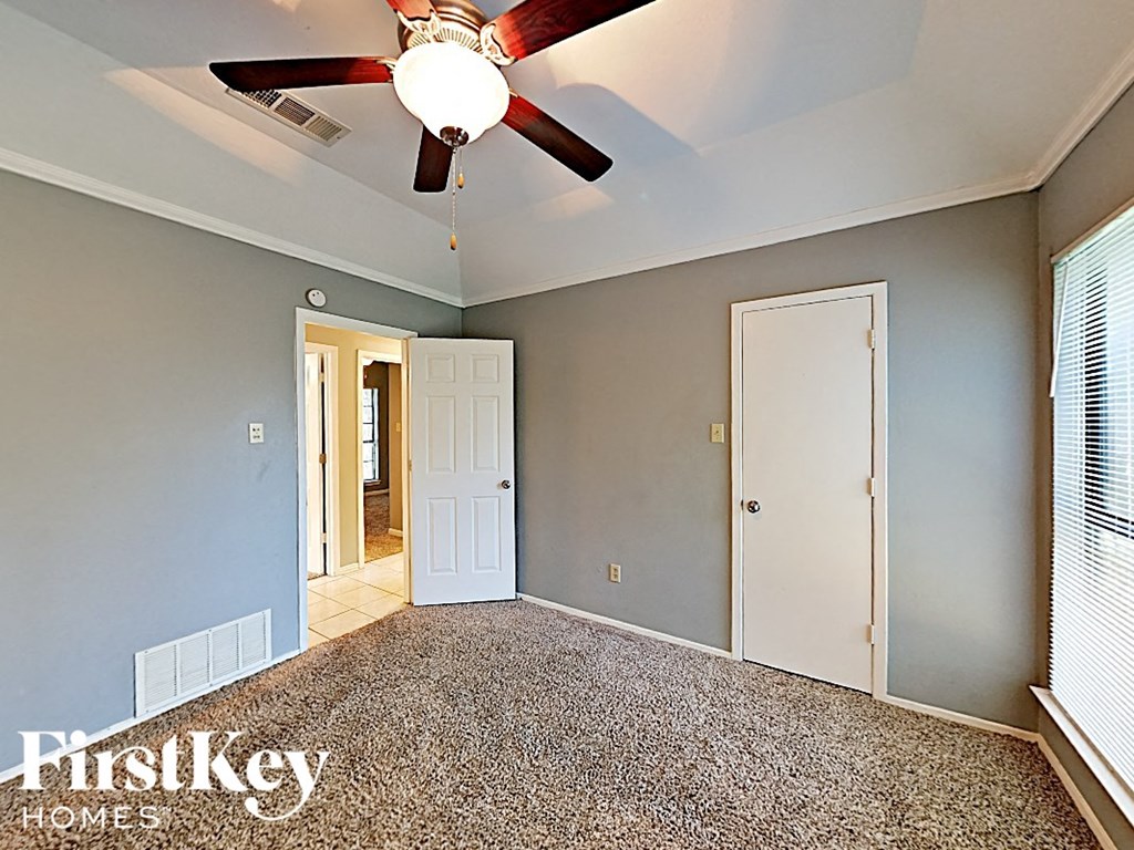 the master bedroom has a ceiling fan and a door to the bathroom