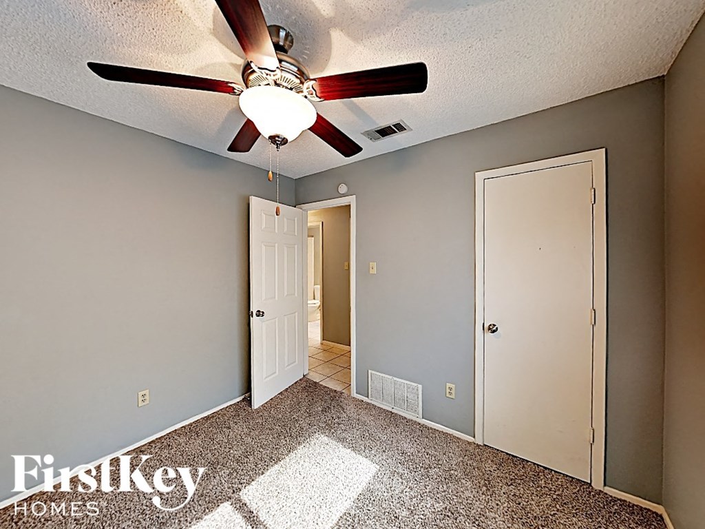 the master bedroom has a ceiling fan and a door to the bathroom