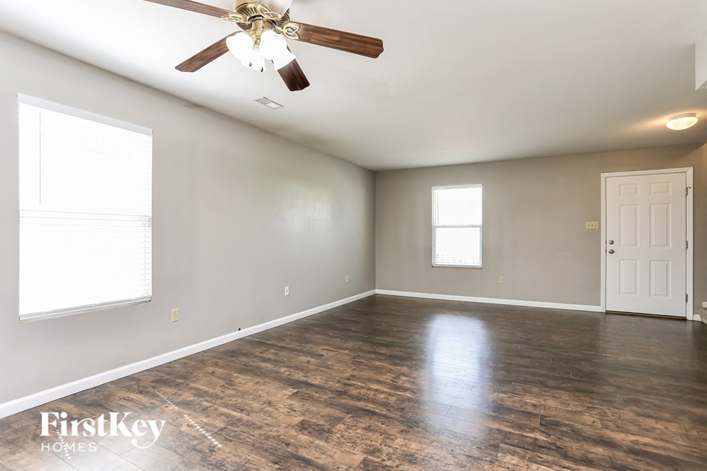 an empty living room with a ceiling fan and a white door