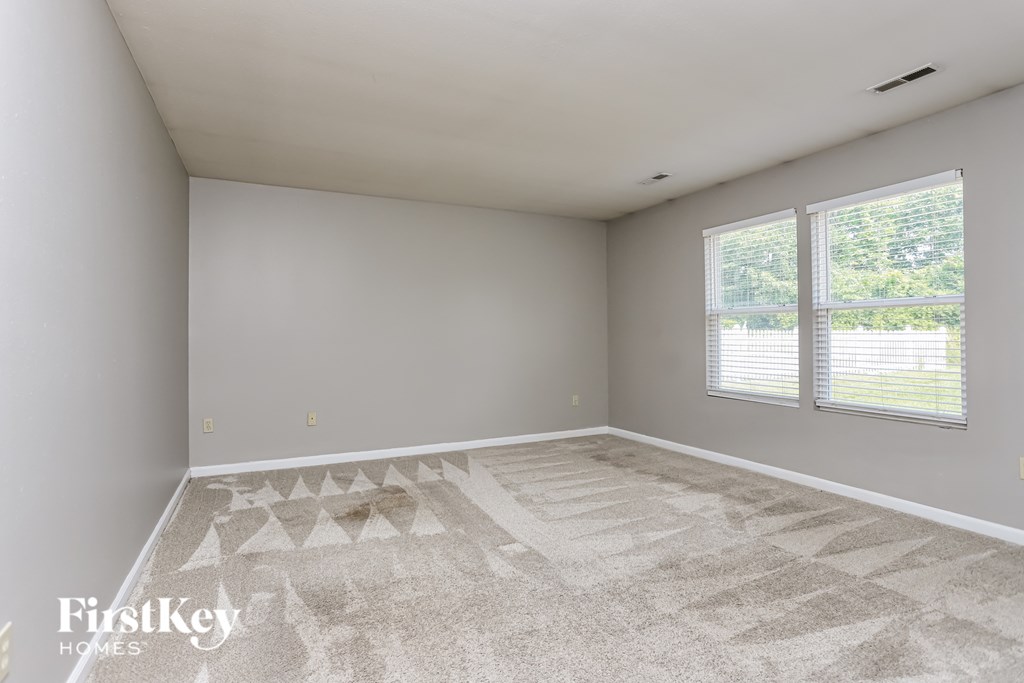 a bedroom with a large window and a carpeted floor