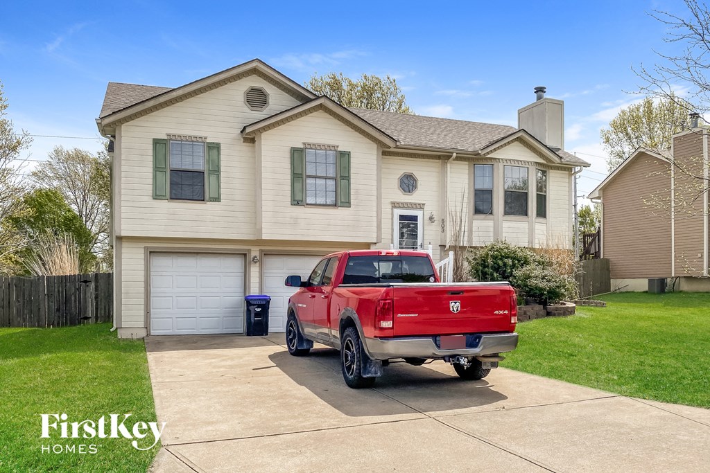 A red pickup truck is parked in front of a two-story house.