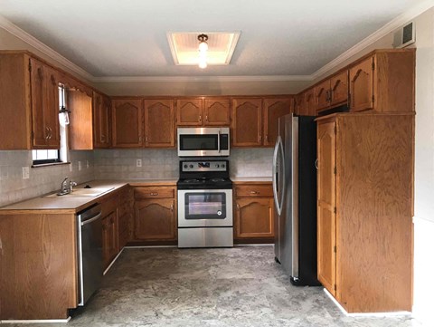 A kitchen with wooden cabinets and a refrigerator.