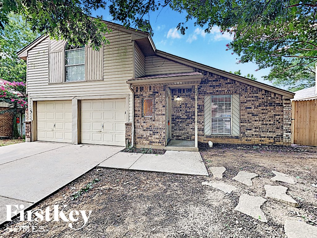 A house with a garage and a driveway in front of it.