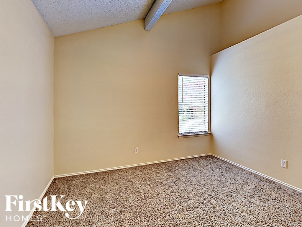 A room with a carpeted floor and a window with blinds.