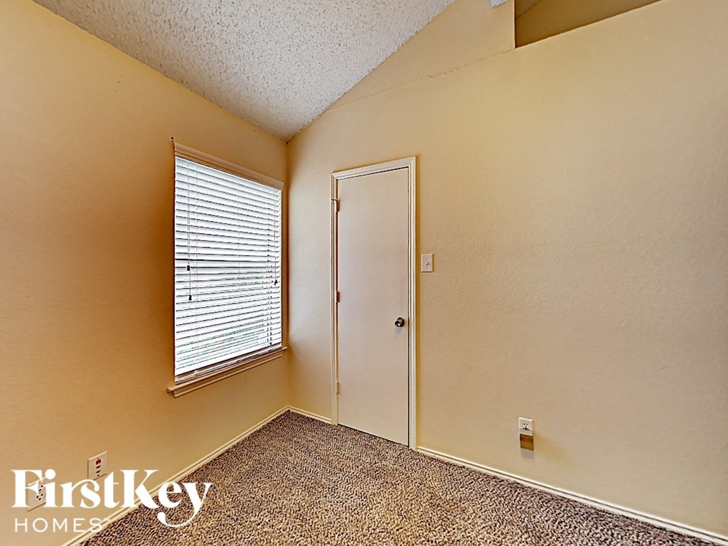 A room with a door, window and carpet.