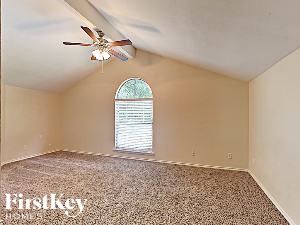 A room with a carpeted floor, a ceiling fan, and a window with blinds.