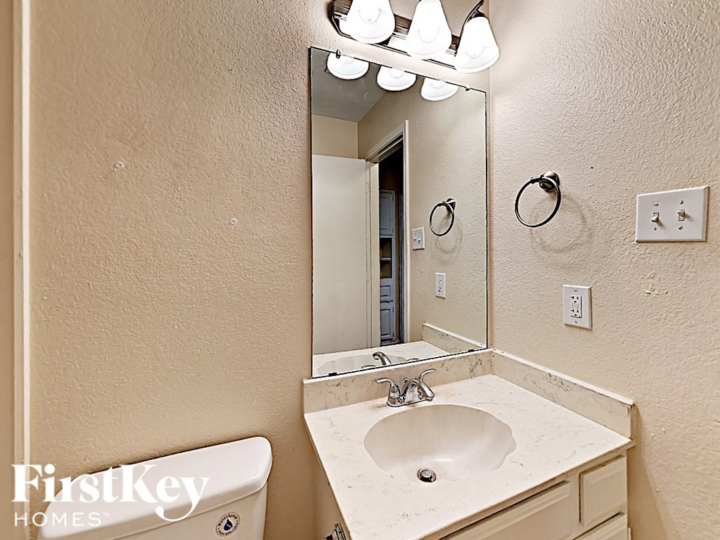 A bathroom with a sink, mirror, and light fixture.
