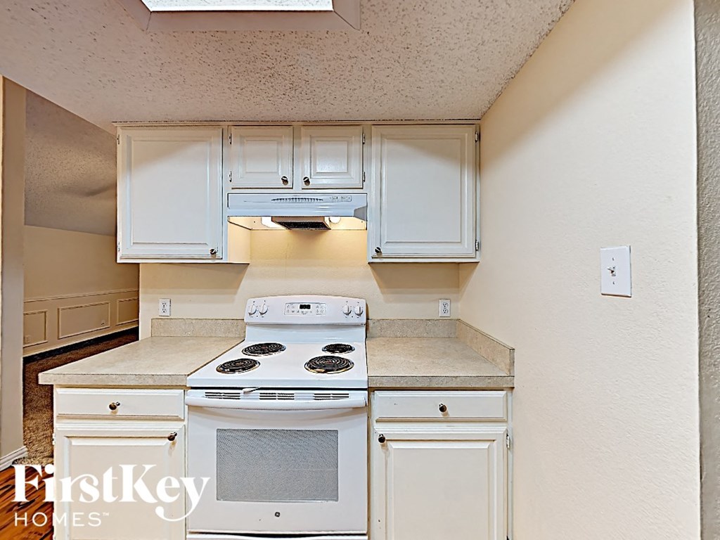 A white stove top oven with a white microwave above it.