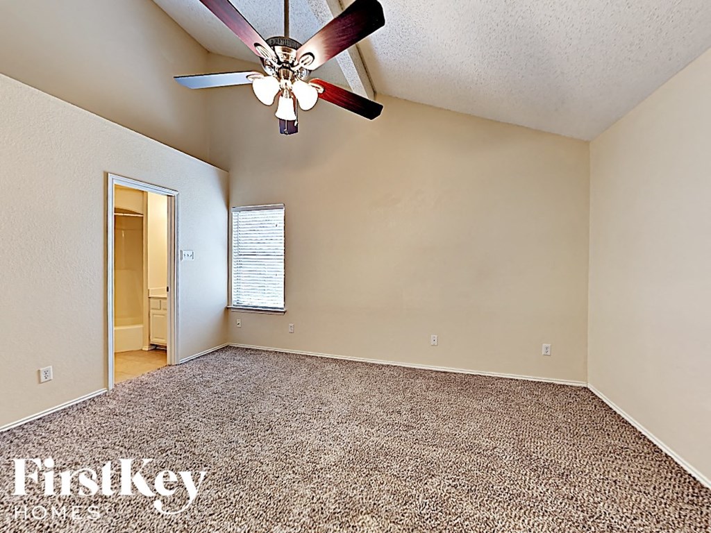 A room with a carpet floor and a ceiling fan.