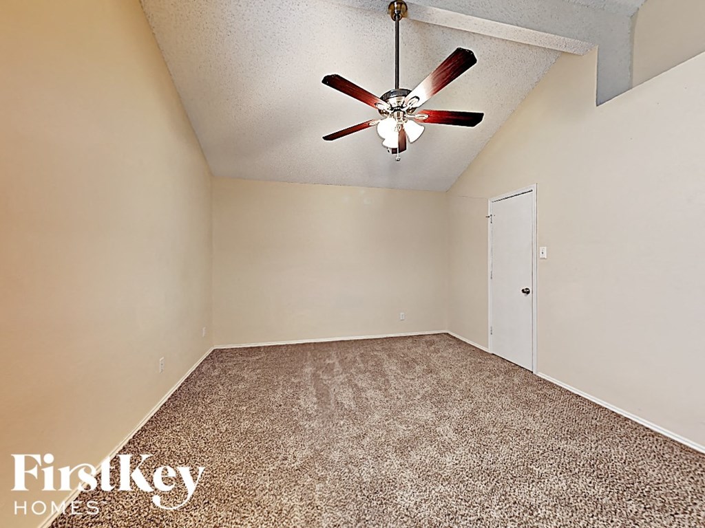 A room with a ceiling fan and carpeted floor.