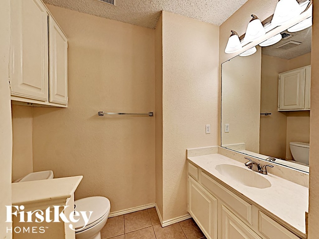 A bathroom with a toilet, sink and mirror.