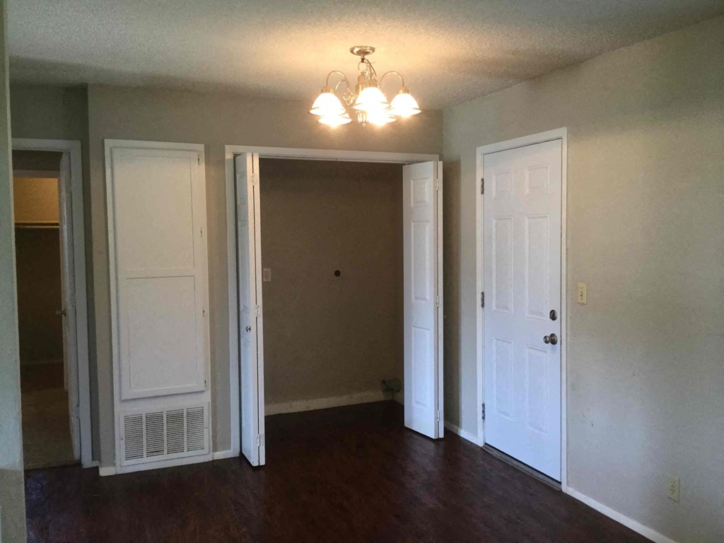 an empty living room with three doors and a chandelier