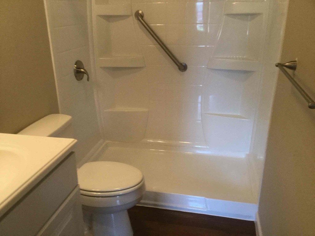 a white bathroom with a toilet and a shower