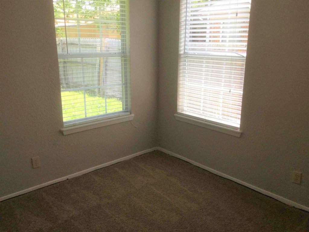 an empty room with two windows with blinds