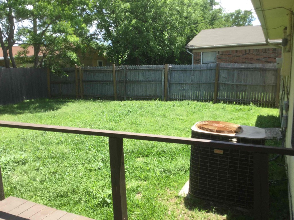 a backyard with a grill and a fence
