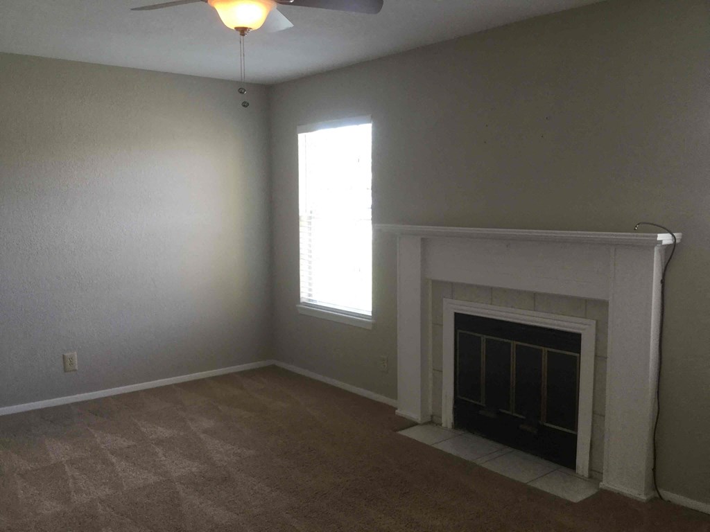 an empty living room with a fireplace and a window
