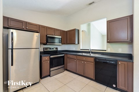 A kitchen with brown cabinets and a stainless steel refrigerator.