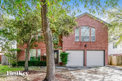 a brick house with two garage doors and trees