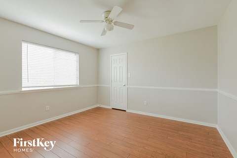 a bedroom with wood floors and a ceiling fan