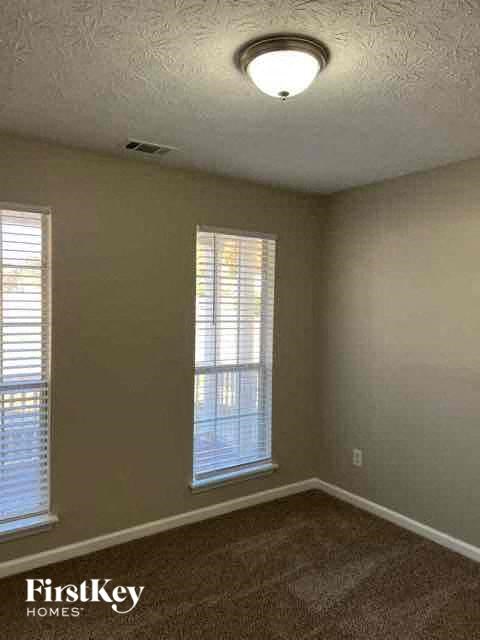 an empty room with two windows and a ceiling light