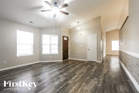 A spacious room with wood flooring and a ceiling fan.
