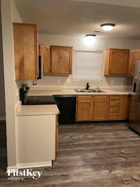 A kitchen with wooden cabinets and a black dishwasher.