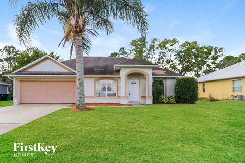 a pink house with a palm tree in the yard