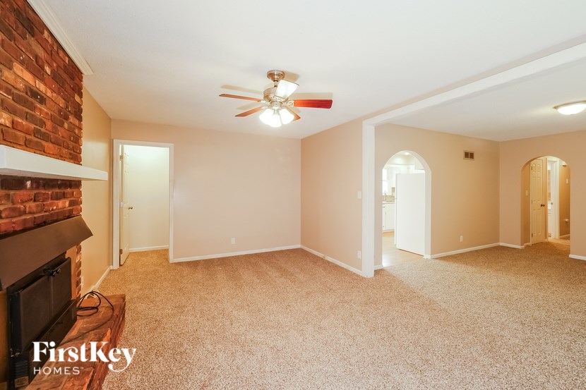 A spacious room with a brick fireplace and a ceiling fan.