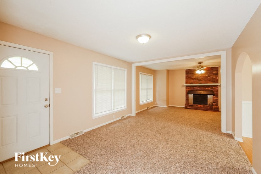 A spacious living room with a fireplace and a carpeted floor.