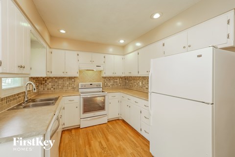 A kitchen with white cabinets and a stove top oven.
