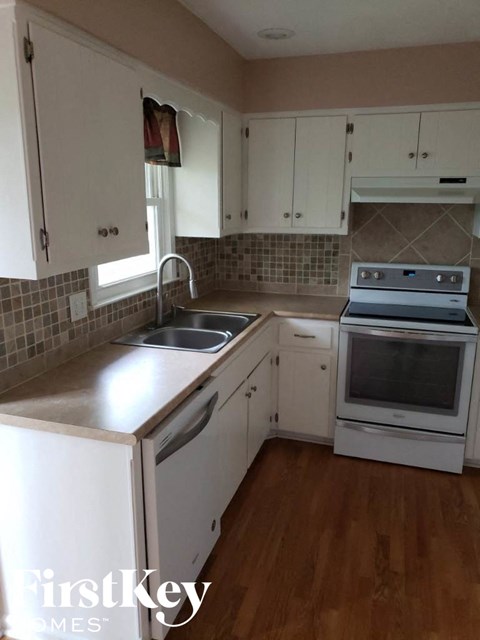 A kitchen with white cabinets and a wooden floor.