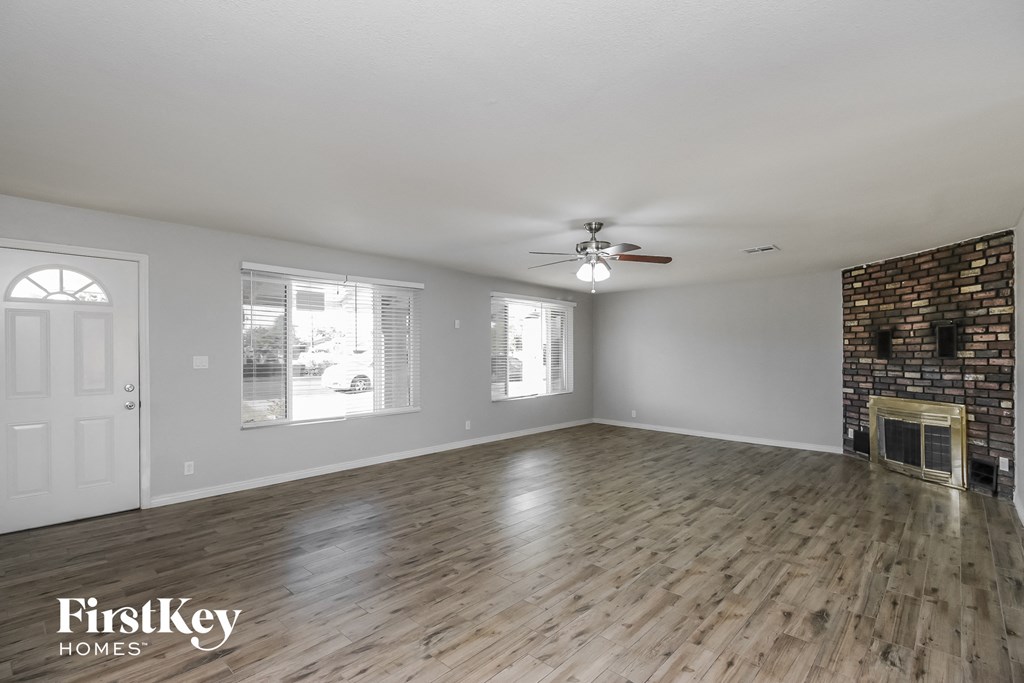 an empty living room with a fireplace and a ceiling fan