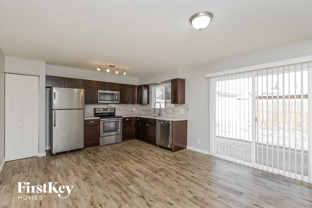 an open kitchen with stainless steel appliances and wood flooring