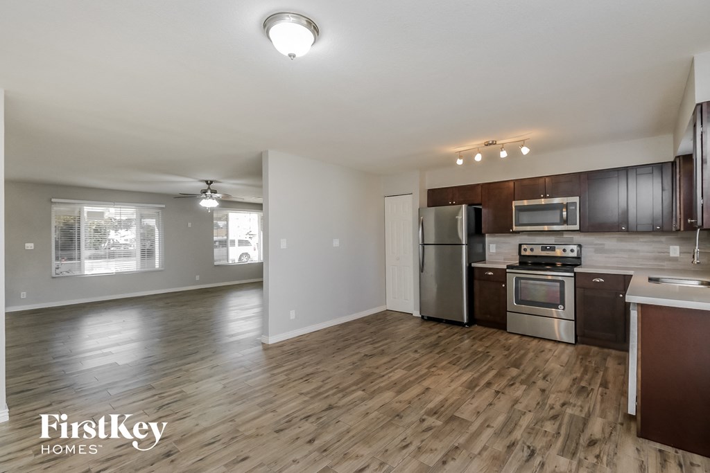 an open kitchen and living room with wood flooring and stainless steel appliances