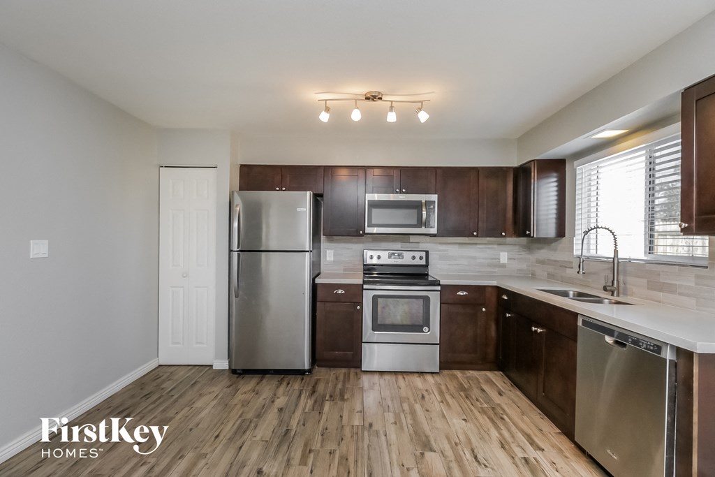an empty kitchen with stainless steel appliances and wooden cabinets