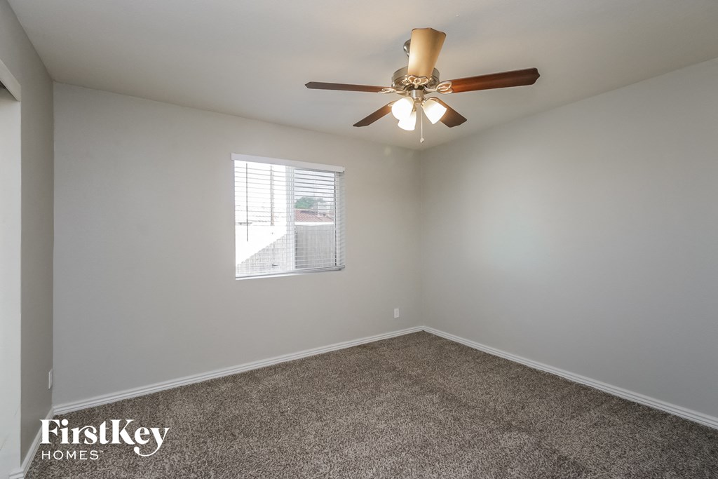 an empty bedroom with a ceiling fan and a window