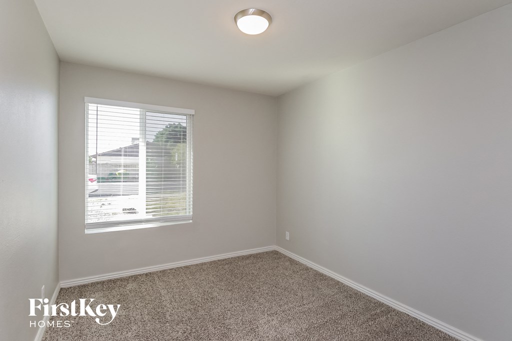 a bedroom with a window and a carpeted floor