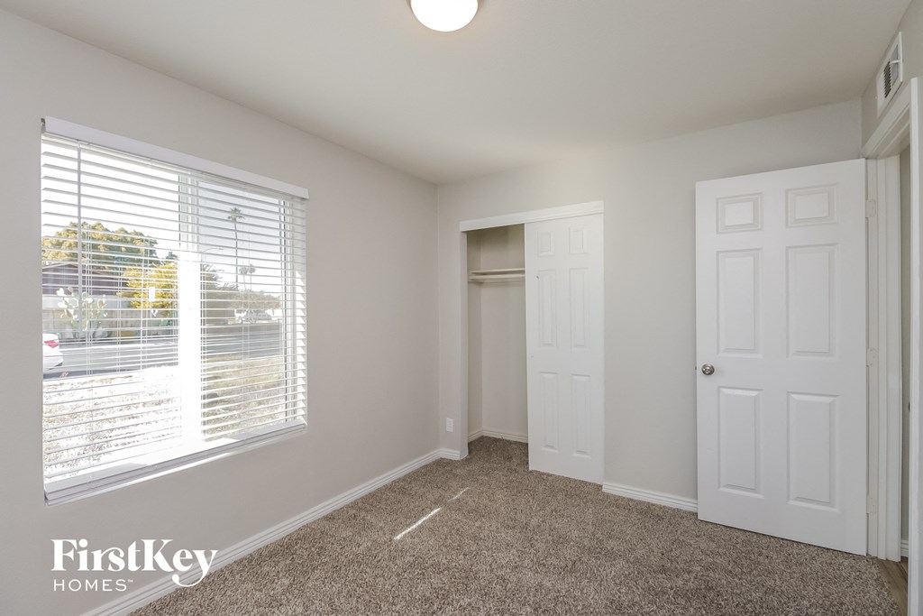 a bedroom with a window and a closet and a white door