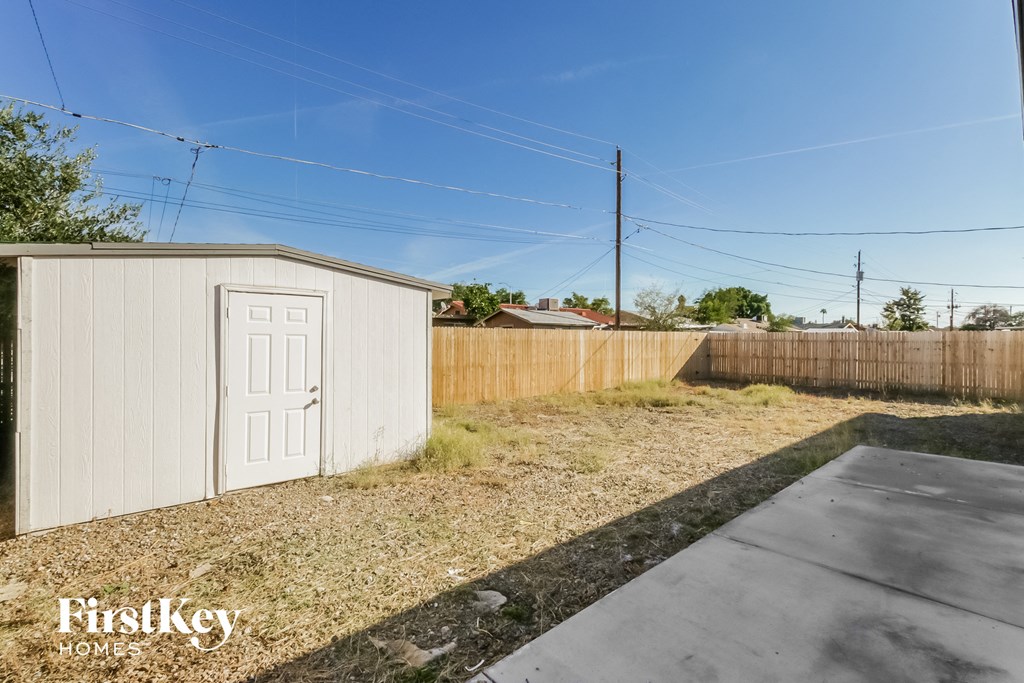 a small backyard shed with a white door and a wooden fence
