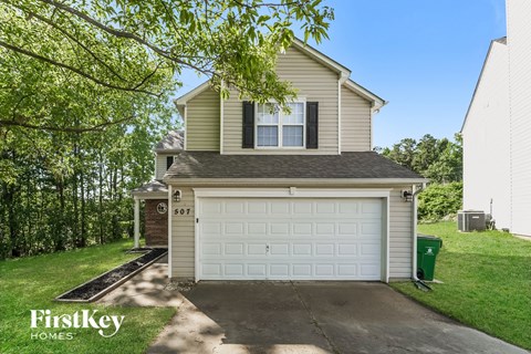 a white garage door on a tan house with a driveway
