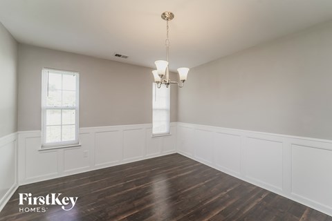 a dining room with white walls and wood floors and a chandelier