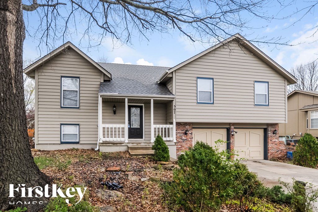 A house with a front porch and a tree in front of it.
