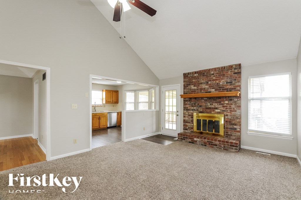 A spacious living room with a fireplace and a ceiling fan.